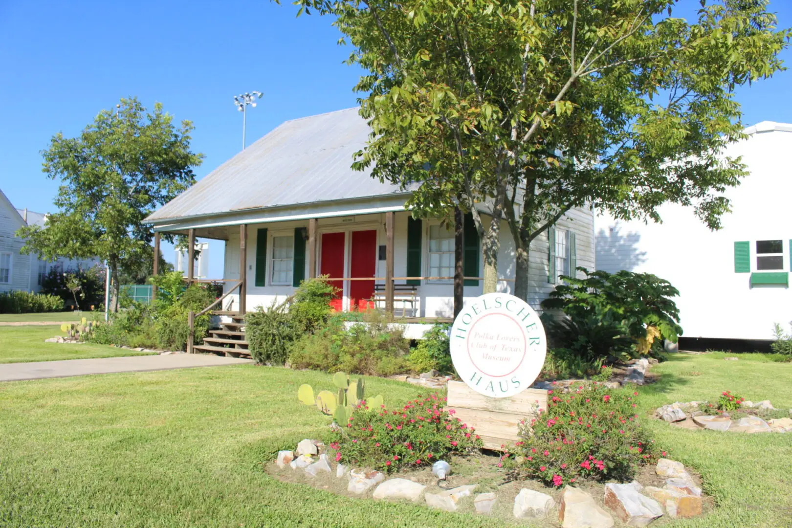 A small white house with red door and sign in front of it.