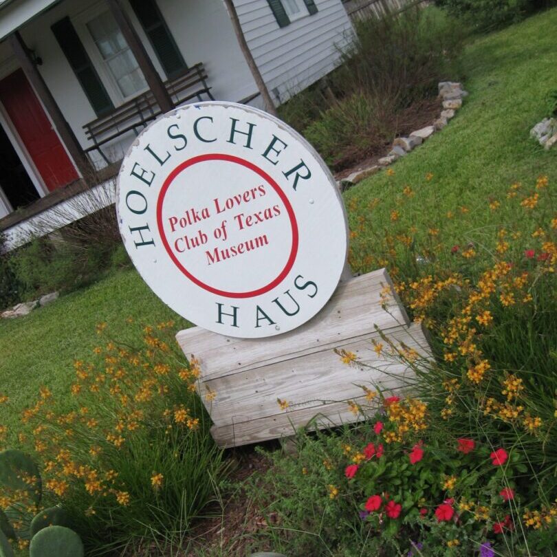 A sign in front of some flowers and grass